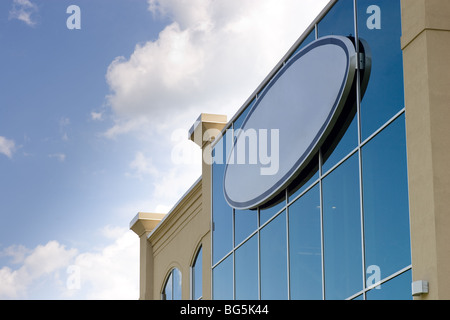 Un signe vide circulaire à l'angle d'un immeuble de bureaux, avec un ciel bleu et nuages dispersés dans l'arrière-plan. Banque D'Images