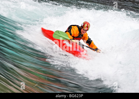 Andrew Jobe pagaies de kayak une par une vague sur la rivière Kananaskis, comté de Kananaskis, Alberta, Canada Banque D'Images