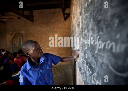 Une jeune fille écrit sur un tableau noir dans une salle de classe de Amuria, en Ouganda. Banque D'Images