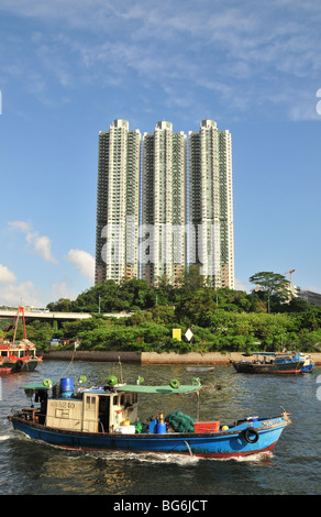 Portrait d'un petit bateau de pêche vers l'ouest, trois immeubles de grande hauteur, le port d'Aberdeen, Hong Kong, Chine Banque D'Images