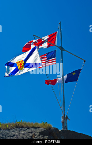 Le Canada, la Nouvelle-Écosse, acadienne, et USA drapeaux flottants à partir d'un mât au phare du cap Forchu, Yarmouth Port, Cape Forchu Banque D'Images