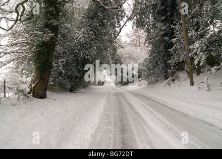 Une petite route dans la campagne anglaise du Hampshire après une importante chute de neige avec les traces de pneus dans la neige Banque D'Images