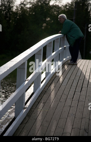 Femme finlandaise âgée penchée sur le parapet du pont en bois, Finlande Banque D'Images
