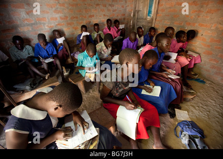 Les filles et les garçons apprennent dans une sombre salle de classe sans un bureau dans Amuria, est de l'Ouganda. Banque D'Images