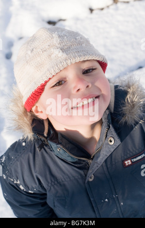 4 ans garçon hispanique joue dans la neige fraîchement tombée dans sa cour d'avec sa mère. Modèle droit est libéré. Banque D'Images