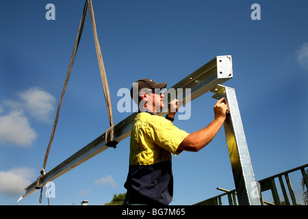 Un travailleur de la construction place une poutre d'acier au cours de la construction d'une maison. Banque D'Images