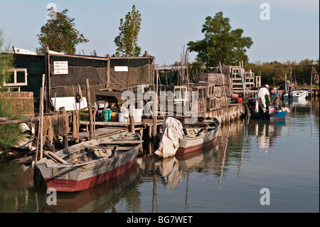 Deux pêcheurs chargent leur bateau avec des pots de crabe sur une petite île près de Burano sur la lagune vénitienne, Venise, Italie Banque D'Images