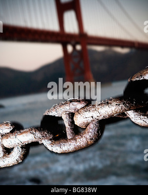 Gros plan d'une chaîne de métal rouillé liens avec le Golden Gate Bridge en arrière-plan, San Francisco, CA. Banque D'Images