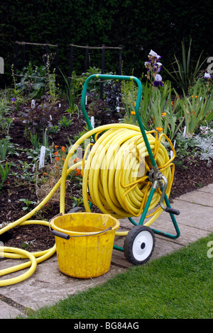 Un enrouleur de tuyau de jardin PRÊT À ÊTRE UTILISÉ SUR UNE BORDURE DE JARDIN. Banque D'Images