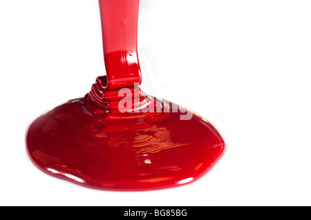 L'encre de l'imprimante, le rouge étant versé sur une surface blanche de l'encre à partir d'un bain à remous. Banque D'Images