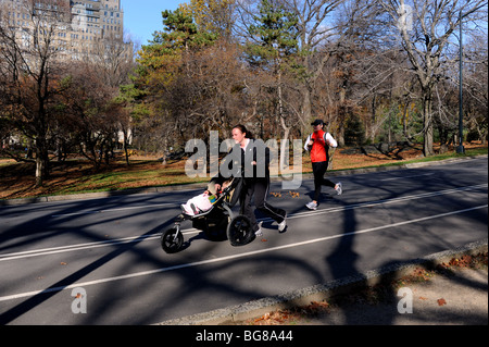 Une femme reprend sa course avec un bébé en poussette dans Central Park, New York USA Banque D'Images