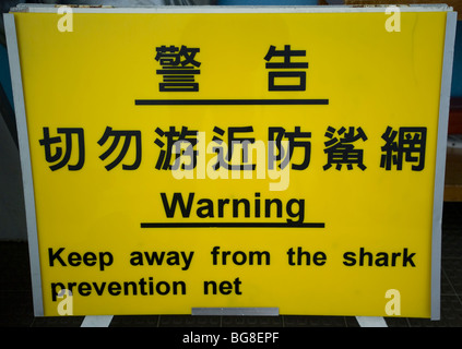 Un signe à une plage de Hong Kong met en garde les visiteurs à rester loin de la prévention requin net en chinois et en anglais. Banque D'Images