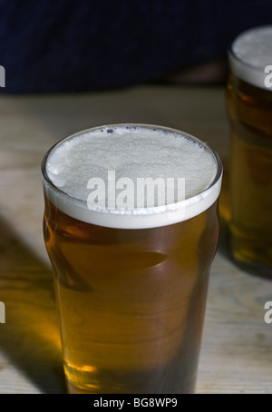 Pintes de bière amère orange doré frotté sur table de pub en bois Banque D'Images