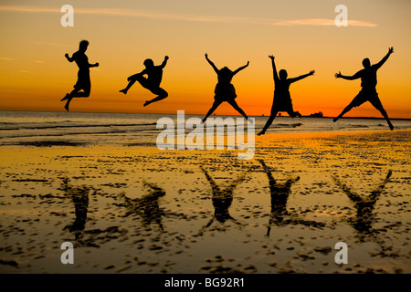 Les jeunes adultes élevés en saut à pied sur la plage. Banque D'Images