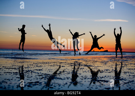 Les jeunes adultes élevés en saut à pied sur la plage. Banque D'Images