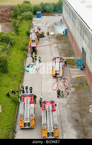 De nombreux camions de pompiers à l'extérieur grand feu d'usine d'en haut Banque D'Images