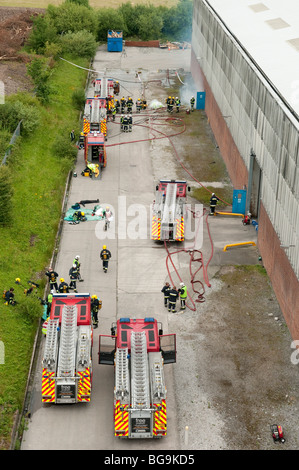 De nombreux camions de pompiers à l'extérieur grand feu d'usine d'en haut Banque D'Images