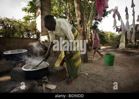 Une femme riz cuit sur un feu ouvert, dans un orphelinat dans la région de Kilimandjaro, Tanzanie, Afrique de l'Est. Banque D'Images