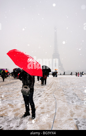 Paris, France, femme tenant un parapluie rouge en scène d'hiver, gens dans la tempête de neige, touristes se tenant près de la Tour Eiffel sur la sombre place Trocacacadéro Banque D'Images