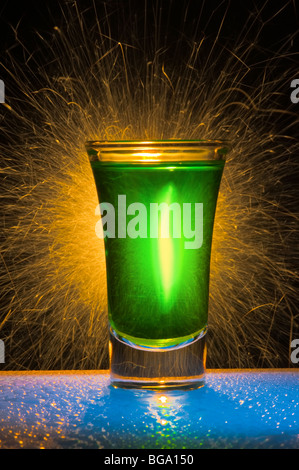 Le verre de vin pour un cocktail avec de l'alcool de couleur verte contre les feux de Bengale avec réflexion Banque D'Images