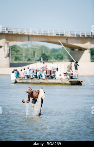L'homme pêche dans une rivière, en bateau à passagers. L'état d'Orissa, en Inde. Banque D'Images