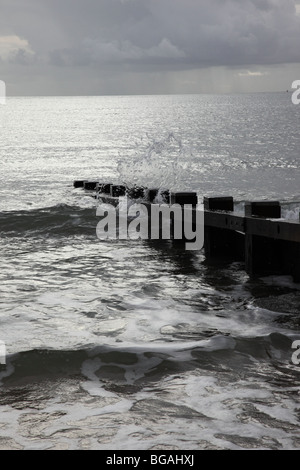 Image en noir et blanc d'une vague qui s'est brisée contre une groyne à Swanage, Dorset, Angleterre Banque D'Images