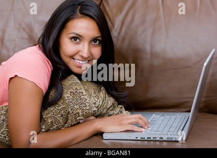 Jeune femme dans la vingtaine, travaille sur son ordinateur portable tout en vous relaxant à la maison. Banque D'Images