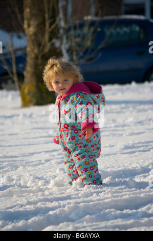 Baby Girl dans la neige vêtu d'un manteau chaud coloré Banque D'Images