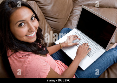 Jeune femme dans la vingtaine, travaille sur son ordinateur portable tout en vous relaxant à la maison. Banque D'Images