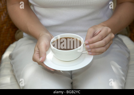 Woman holding tasse de café sur ses genoux Banque D'Images
