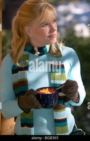 Woman eating chili en dehors sur le porche dans la neige Banque D'Images