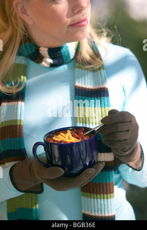 Woman eating chili en dehors sur le porche dans la neige Banque D'Images