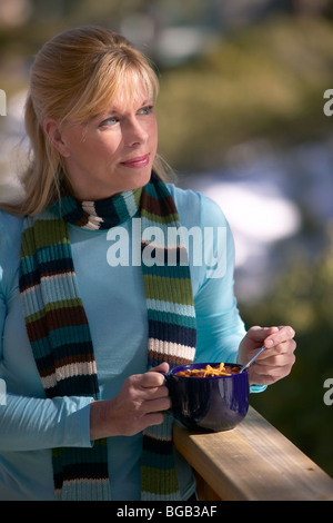 Woman eating chili en dehors sur le porche dans la neige Banque D'Images