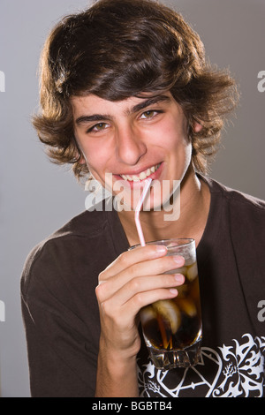 Teenage boy drinking soda dans un verre avec une paille, Smiling, Portrait Banque D'Images