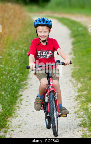 Un garçon, 7 ans, École de la bicyclette sur une route de terre Banque D'Images