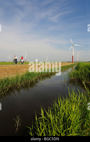 Les cyclistes en face des éoliennes, Friesia Sexbierum, Hollande, Pays-Bas, Europe, Banque D'Images
