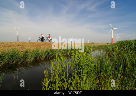 Les cyclistes en face des éoliennes, Friesia Sexbierum, Hollande, Pays-Bas, Europe, Banque D'Images