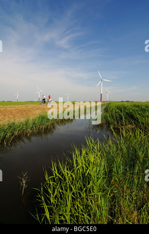 Les cyclistes en face des éoliennes, Friesia Sexbierum, Hollande, Pays-Bas, Europe, Banque D'Images