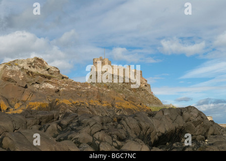 Insolite vue créative différente du château de Lindisfarne, Holy Island, Northumberland, Royaume-Uni. Mai. Vue depuis les rochers sur le rivage. Banque D'Images