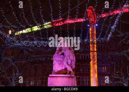 Les lumières de Noël se baigner la statue à Leicester Square pendant la fête foraine de Noël Banque D'Images