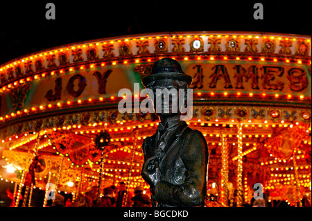 La statue de Charlie Chaplin à Leicester Square avec un brillant fairground ride derrière. Banque D'Images