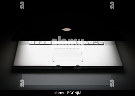 Ordinateur portable d'argent sur un fond noir avec réflexion et de copier l'espace. Banque D'Images