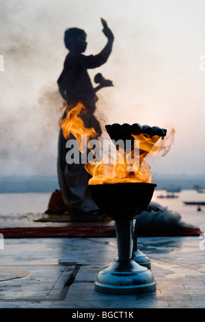 Prêtre hindou adorant Dieu soleil Surya au lever du soleil sur la rive de la rivière Ganges (Mère Ganga) à Varanasi, Inde. Banque D'Images