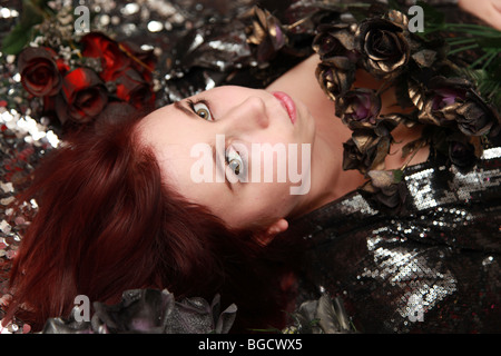 Teenage girl lying sur les fleurs et l'argent. Banque D'Images