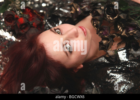 Teenage girl lying sur les fleurs et l'argent. Banque D'Images