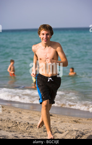 Teen boy running in Swim Trunks et sur la plage, smiling, portrait, Smiling, portrait Banque D'Images