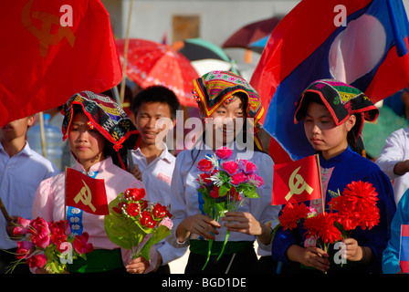 Festival, Tai Dam les filles, habillés en vêtements traditionnels, tenant des drapeaux rouges du Parti Communiste, drapeau national du Laos, Xam Banque D'Images