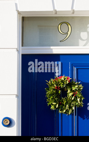 Couronne de houx de Noël sur un début de l'époque victorienne traditionnelle de style Regency / English porte. Banque D'Images