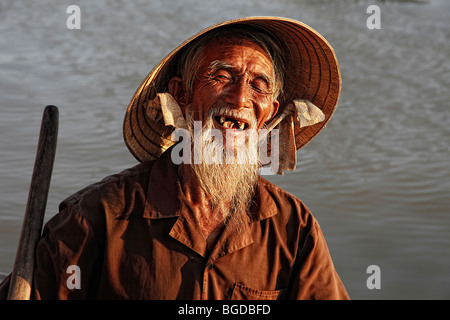 Personnes âgées, souriant pêcheur en barque dans le port de Hoi An, Vietnam, Southeast Asia Banque D'Images