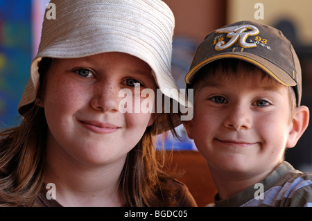 Portrait d'une jeune fille avec des taches de rousseur et un chapeau et un jeune garçon portant une casquette Banque D'Images